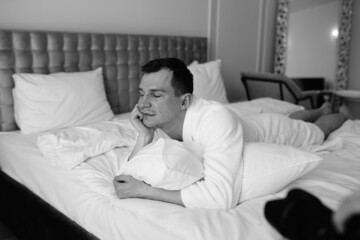 Fototapeta premium in the photo, a smug man in a bathrobe in hotels lying down enjoying the view from the window