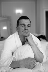 in the photo, a smug man in a bathrobe in hotels lying down enjoying the view from the window