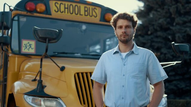 Portrait schoolbus driver standing at yellow vehicle alone looking camera.