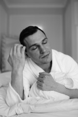 in the photo, a smug man in a bathrobe in hotels lying down enjoying the view from the window