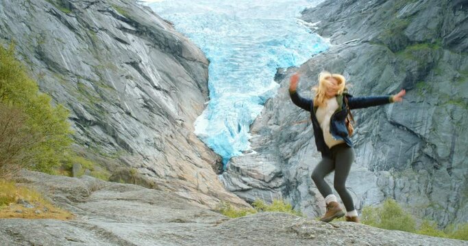 4k video footage of a young woman dancing while exploring the mountains of Briksdal Glacier