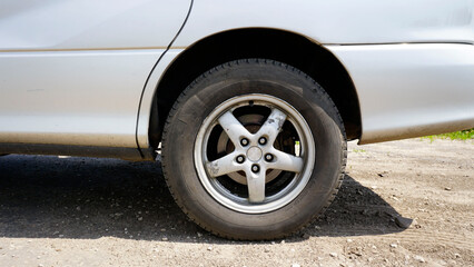 Rear wheel of a car. Silver color. Black rubber. Cast aluminum rim. Sunny day. Disc brakes. Modern car. Close-up.