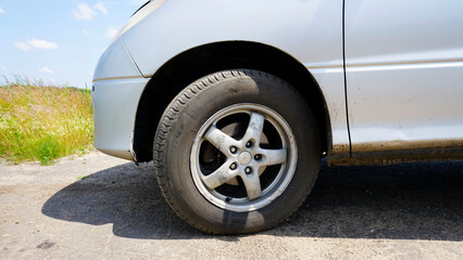The front wheel of a car. Silver color. Black rubber. Cast aluminum rim. Sunny day. Disc brakes. Modern car. Close-up.
