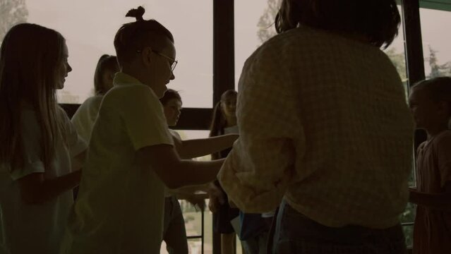 Cruel bullies offending classmate in school hallway. Teenagers pushing boy.