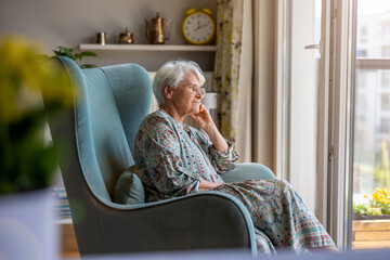 Elderly woman sitting in an armchair in her home
