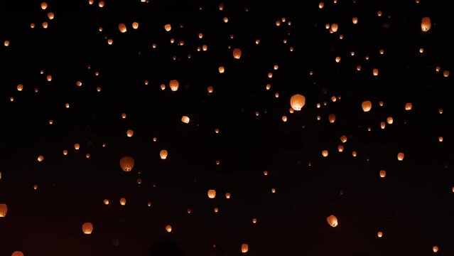 The nights sky filled with paper lanterns glowing as they float up and away during celebration.