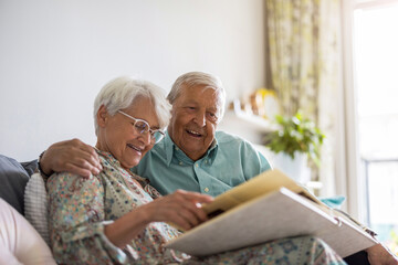 Elderly couple looking at a photo album while sitting on a sofa
