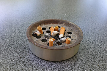 Cigarette butts thrown into an ashtray close-up