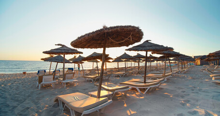 Summer beach resort. Beach reed umbrella from Tunisia. Sea water on the sunset. Vacation and travel concept.