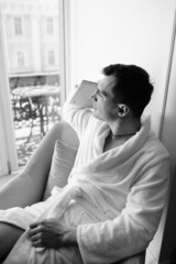 in the photo, a smug man in a bathrobe in hotels lying down enjoying the view from the window