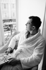 in the photo, a smug man in a bathrobe in hotels lying down enjoying the view from the window