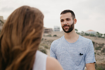 A Hispanic man is staring at his girlfriend in the highland park in Spain. A couple of tourists are enjoying each other on a date at sunset in Valencia.