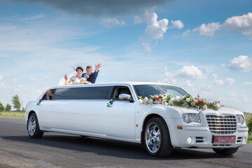 The bride and groom near the wedding limousine. - obrazy, fototapety, plakaty
