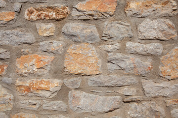 Stonewall is made of light orange and grey coloured stones. Front view and close up.