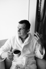 in the photo, a smug man in a bathrobe in hotels lying down enjoying the view from the window