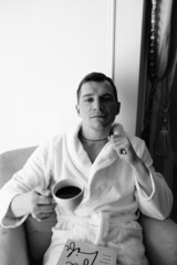 in the photo, a smug man in a bathrobe in hotels lying down enjoying the view from the window