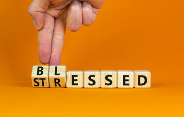 Blessed or stressed symbol. Businessman turns wooden cubes and changes the concept word Stressed to Blessed. Beautiful orange table orange background. Business blessed or stressed concept. Copy space.