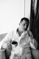 in the photo, a smug man in a bathrobe in hotels lying down enjoying the view from the window