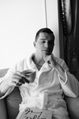 in the photo, a smug man in a bathrobe in hotels lying down enjoying the view from the window