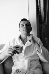 in the photo, a smug man in a bathrobe in hotels lying down enjoying the view from the window
