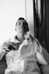 in the photo, a smug man in a bathrobe in hotels lying down enjoying the view from the window