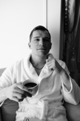 in the photo, a smug man in a bathrobe in hotels lying down enjoying the view from the window