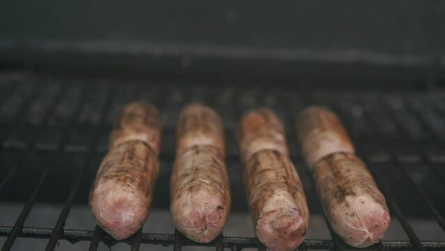 Spicy Sausages Being Grilled Over Bright Glowing Coals Broasting On Fire. Lunch Celebration Party Barbecue. Outdoor Cooking. Cook Prepares Oriental Dish In Kitchen. Junk Food, Healthy Lifestyle.