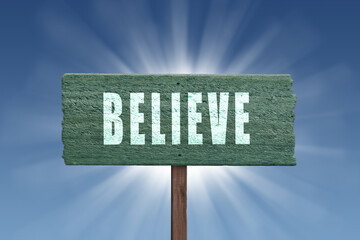 The word Believe written on a sign in nature.