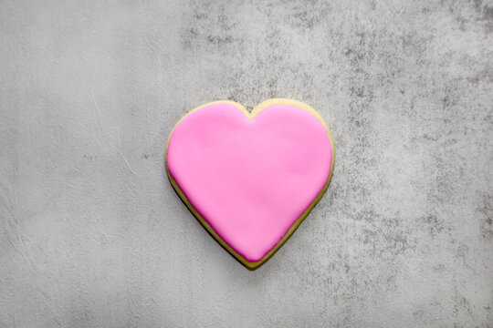 A heart shaped cookie with pink royal icing for Valentine's day with space for text.