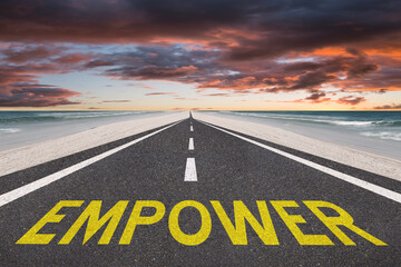 The word Empower on a highway at the beach leading into the sunset.