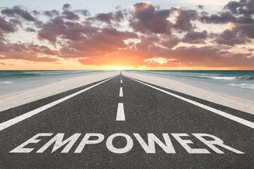 The word Empower on a highway at the beach leading into the sunset.