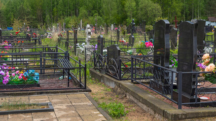 Fototapeta na wymiar City cemetery with fresh graves, wooden and stone gravestones, metal crosses. City geaveyard.