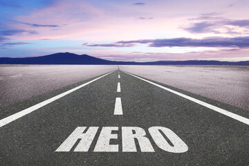 The word Hero on a road at sunset leading to the horizon for motivational concept.