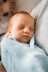 Close-up portrait of newborn boy on mother's hand. Baby boy sleeping in mother's arms. Selective focus. Film grain