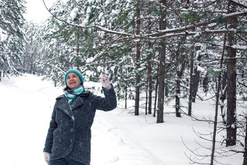Fototapeta na wymiar A woman enjoys a winter, frosty day, a walk in a pine forest