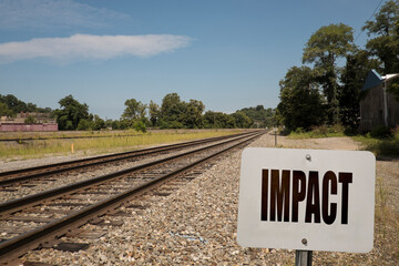 Impact sign with train tracks in the background.