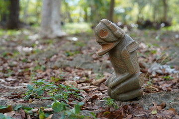 Taino Antique Stone Cemi Idol God Figure standing over rocks on the ground, close up. Taino...