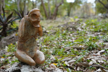 Taino Antique Stone Cemi Idol God Figure standing on rocks on the ground, close up. Taino Mythology.