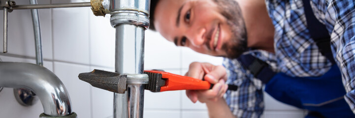 Plumber Repairing Sink In Bathroom