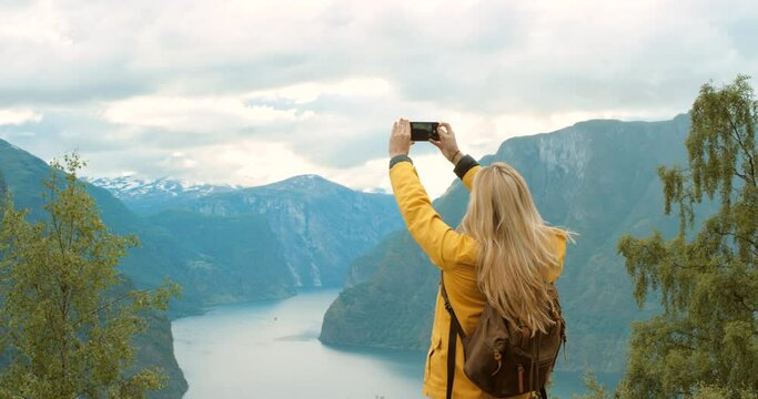 4k video footage of an unrecognisable woman standing and using her cellphone to take photos of Geiranger Fjord