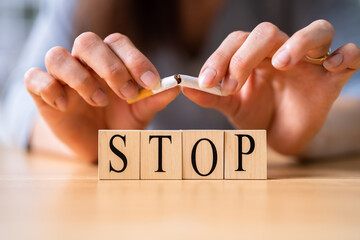 Woman Breaking Cigarette Over Wooden Stop Blocks