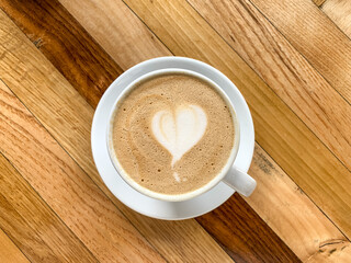 A cup of coffee latte On a wooden table. A mug of flat white coffee on a wooden background. Coffee art. Heart flower shape latte art. Copy space