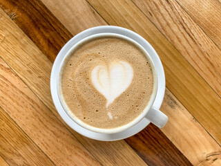 A cup of coffee latte On a wooden table. A mug of flat white coffee on a wooden background. Coffee art. Heart flower shape latte art. Copy space