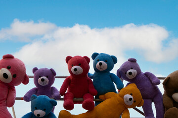 Colorful teddy bears looking from top to down ,with lovely clouds behind them
