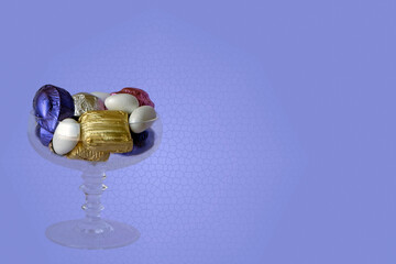 Feast Concept, Traditional Turkish Ramadan sweet sugar candy, and chocolates in glass bowl with purple graphic background. Modern .