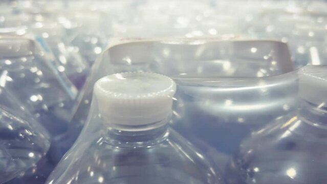 Two-liter bottles of mineral water packed in 6 bottles are in warehouse. Close-up shot. Blurred background