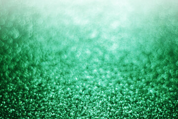 green sparkle glitter background with light bokeh. 