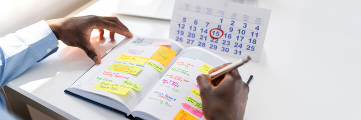 Businessman's Hand Checking Schedule In Diary