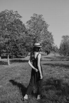 black and white photo from the back of a retro girl in a dress and a hat in the Park