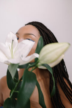 photo of a girl holding a lily flower in front of her face